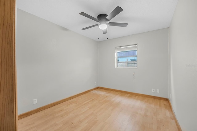 spare room with light wood-type flooring, a ceiling fan, and baseboards