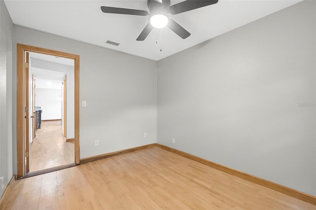 empty room with light wood-type flooring, visible vents, ceiling fan, and baseboards