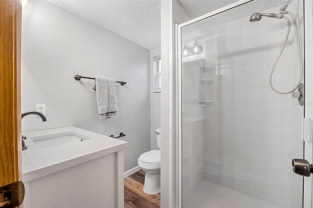 full bathroom with a textured ceiling, toilet, wood finished floors, vanity, and a stall shower