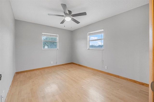 unfurnished room with light wood-type flooring, ceiling fan, a textured ceiling, and baseboards