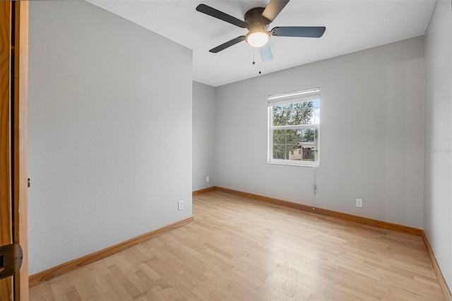 spare room featuring baseboards, a ceiling fan, and light wood-style floors