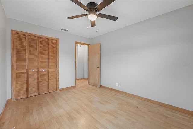 unfurnished bedroom with ceiling fan, light wood-style flooring, visible vents, baseboards, and a closet