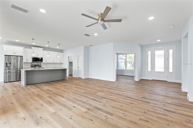 kitchen featuring open floor plan, appliances with stainless steel finishes, visible vents, and white cabinets