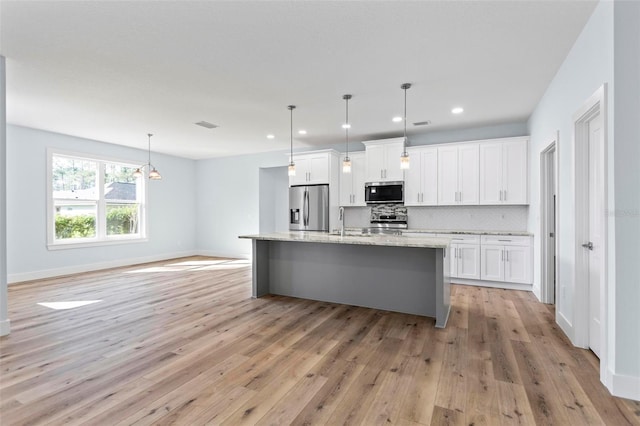 kitchen with light wood-style flooring, a sink, white cabinetry, appliances with stainless steel finishes, and tasteful backsplash