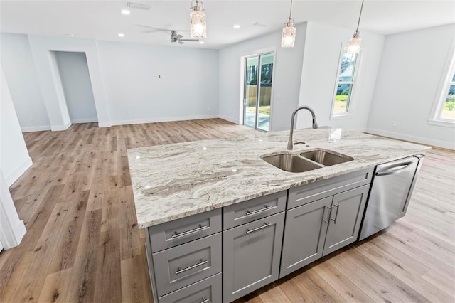 kitchen featuring open floor plan, a sink, gray cabinetry, a healthy amount of sunlight, and stainless steel dishwasher