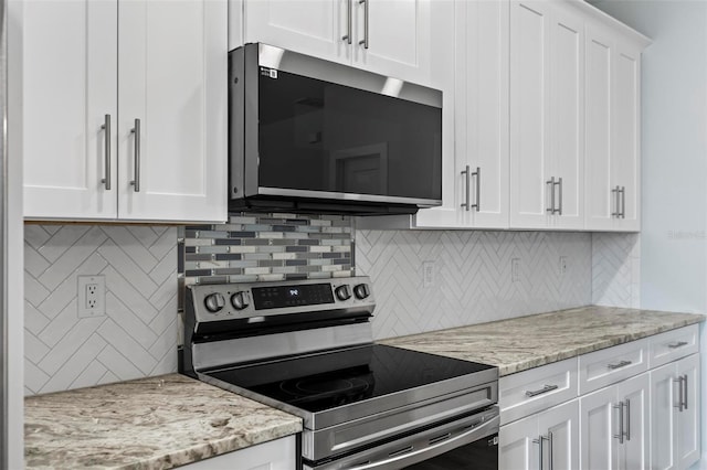 kitchen with appliances with stainless steel finishes, backsplash, light stone counters, and white cabinets