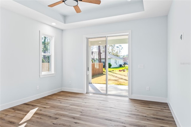 spare room featuring a healthy amount of sunlight, a tray ceiling, and wood finished floors