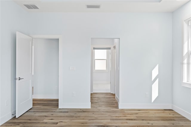 spare room with wood finished floors, visible vents, and baseboards