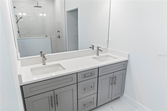 bathroom with marble finish floor, baseboards, a sink, and a marble finish shower