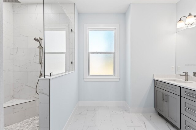 bathroom featuring marble finish floor, a marble finish shower, vanity, and baseboards