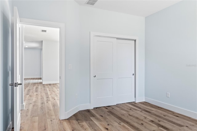 unfurnished bedroom with light wood finished floors, baseboards, and visible vents