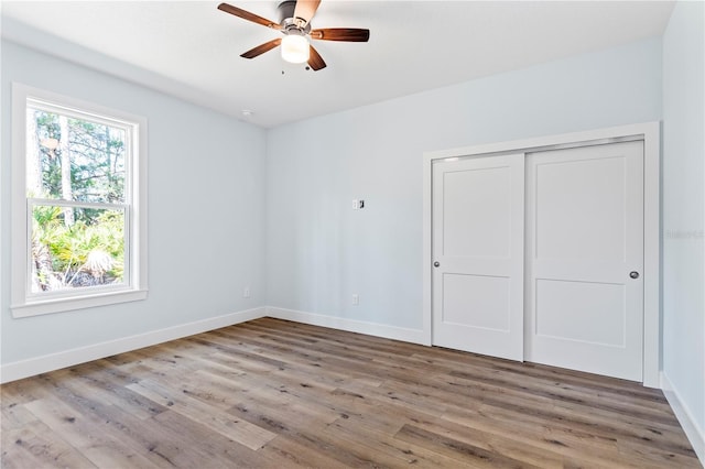 unfurnished bedroom featuring a closet, wood finished floors, a ceiling fan, and baseboards