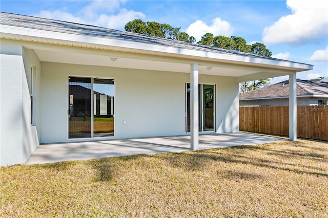 back of property with a lawn, a patio area, fence, and stucco siding