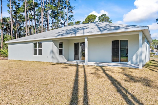 rear view of property featuring a patio area, stucco siding, and a yard