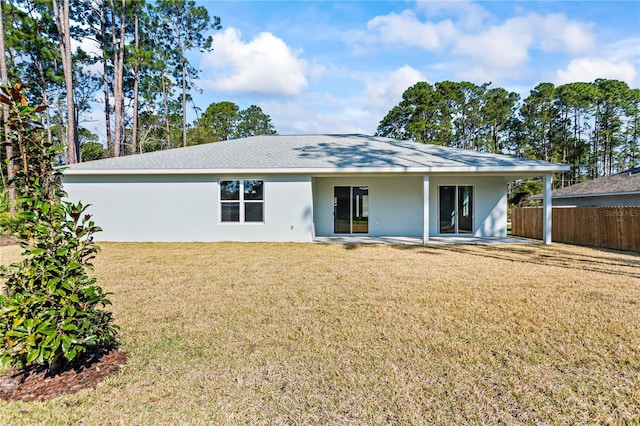 rear view of property with a patio area, fence, a lawn, and stucco siding