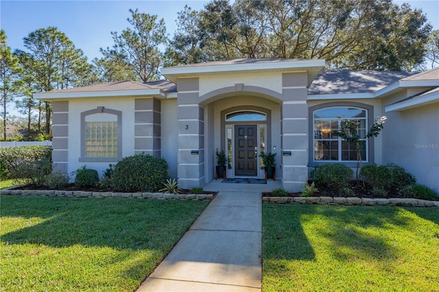 property entrance featuring a lawn and stucco siding