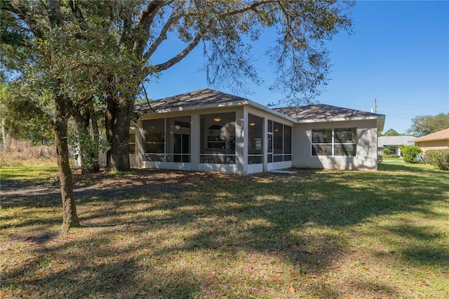 rear view of property featuring a sunroom and a lawn