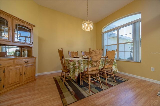 dining space with light wood-style flooring, baseboards, and an inviting chandelier