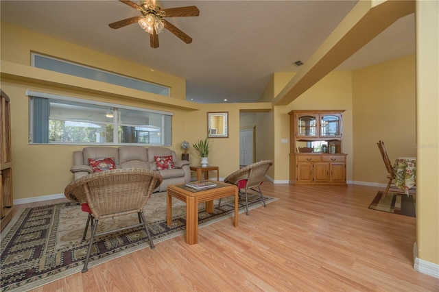 living area featuring light wood-type flooring, visible vents, baseboards, and a textured ceiling