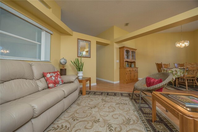 living room with light wood-style floors, baseboards, and an inviting chandelier