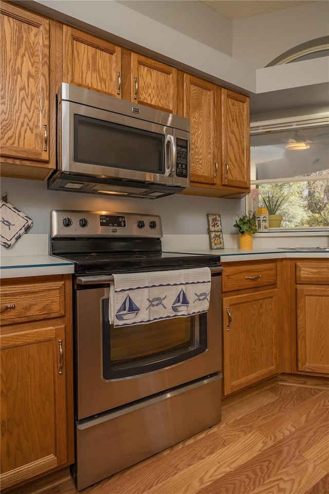 kitchen with appliances with stainless steel finishes, brown cabinets, and light countertops