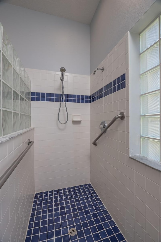 full bath featuring tiled shower and tile walls