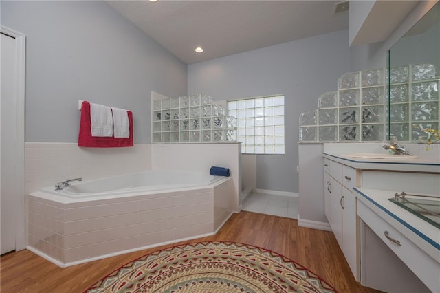 full bath with wood finished floors, visible vents, vanity, baseboards, and a bath