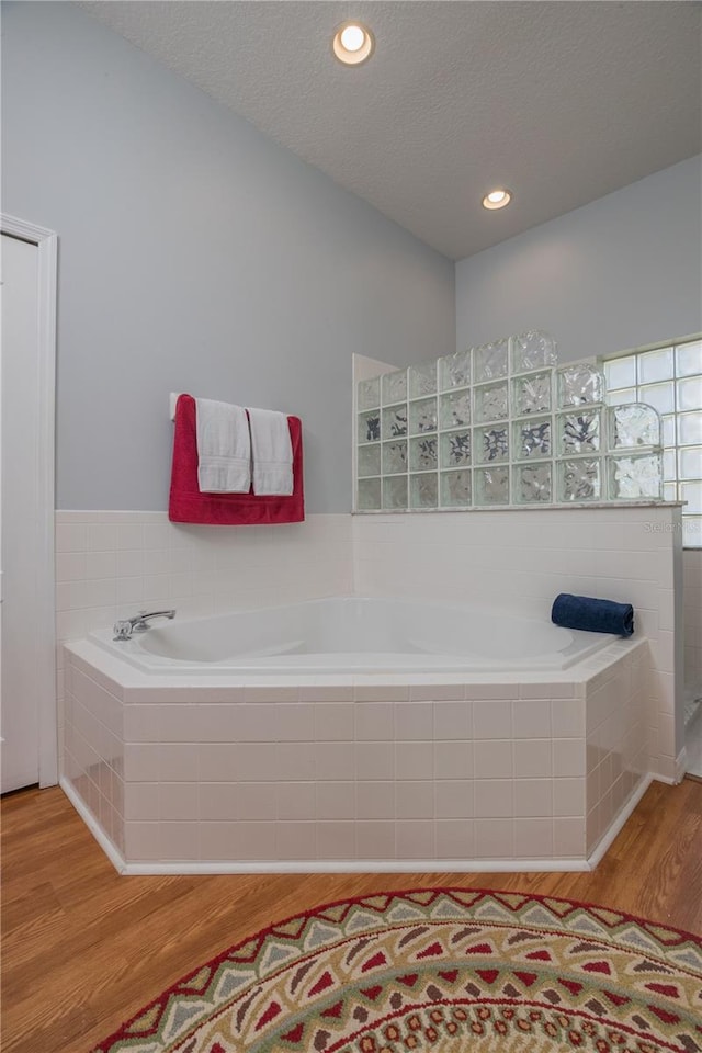 full bathroom with recessed lighting, a textured ceiling, a bath, and wood finished floors