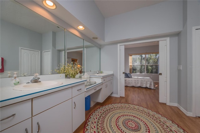 bathroom featuring ensuite bathroom, wood finished floors, vanity, baseboards, and a closet