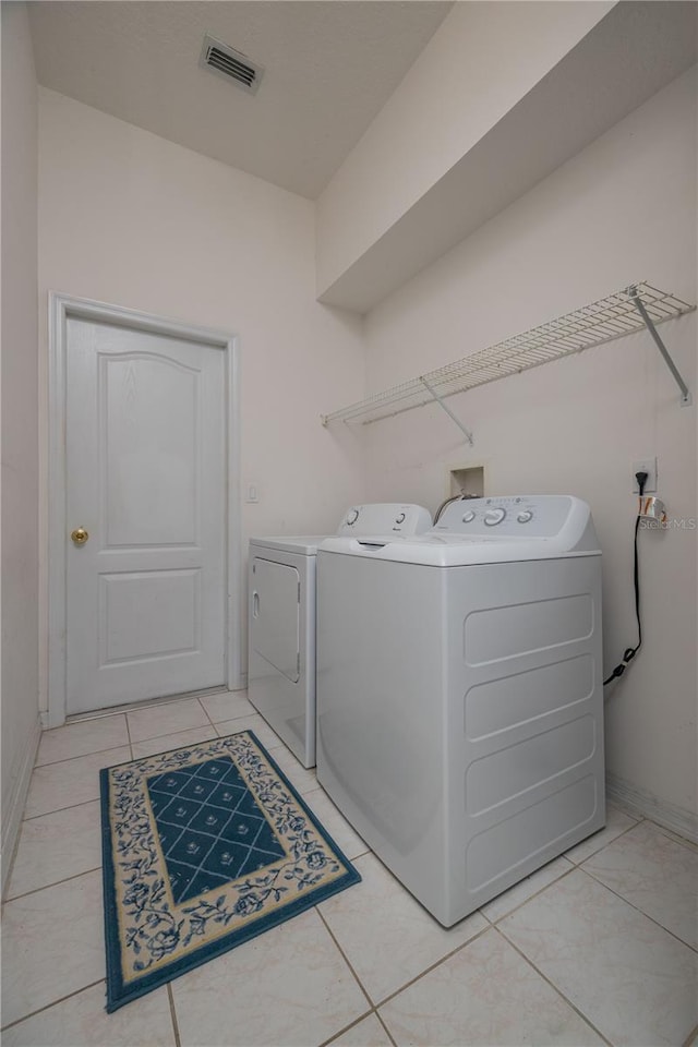 laundry area featuring visible vents, light tile patterned flooring, washer and dryer, laundry area, and baseboards