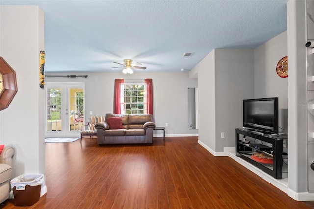 living area featuring a textured ceiling, wood finished floors, visible vents, baseboards, and french doors