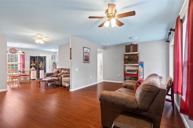 living area with dark wood-style floors, baseboards, and a ceiling fan