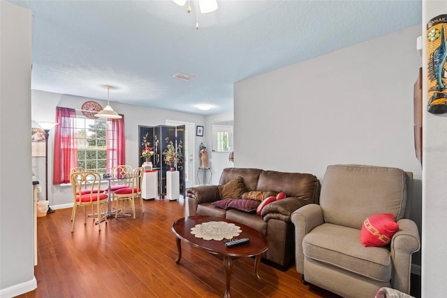 living room with baseboards, visible vents, and wood finished floors