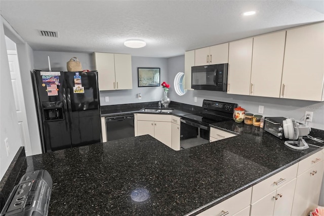 kitchen featuring black appliances, dark stone countertops, visible vents, and a sink