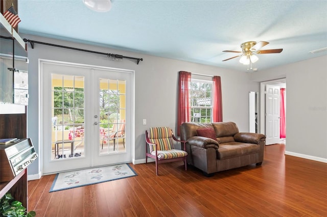 living room featuring french doors, visible vents, baseboards, and wood finished floors