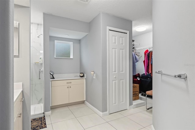 bathroom with a stall shower, a walk in closet, vanity, and tile patterned floors