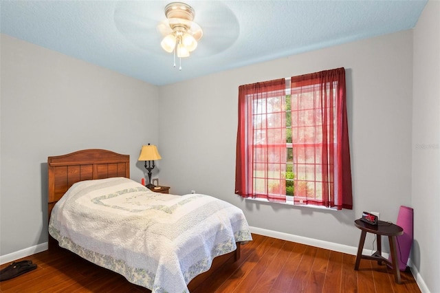 bedroom featuring a textured ceiling, wood finished floors, a ceiling fan, and baseboards