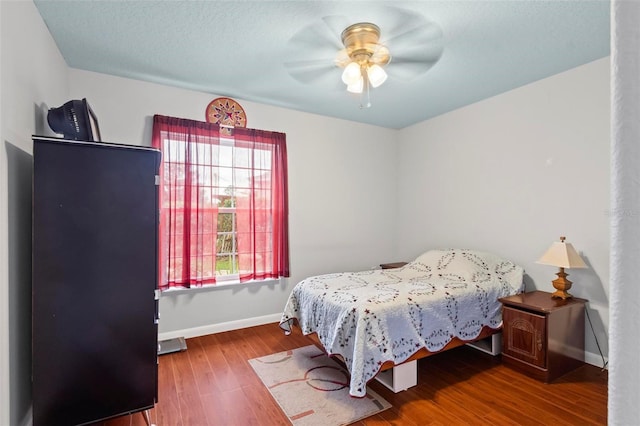 bedroom with ceiling fan, a textured ceiling, baseboards, and wood finished floors