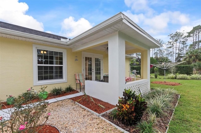 property entrance featuring ceiling fan, a lawn, and stucco siding