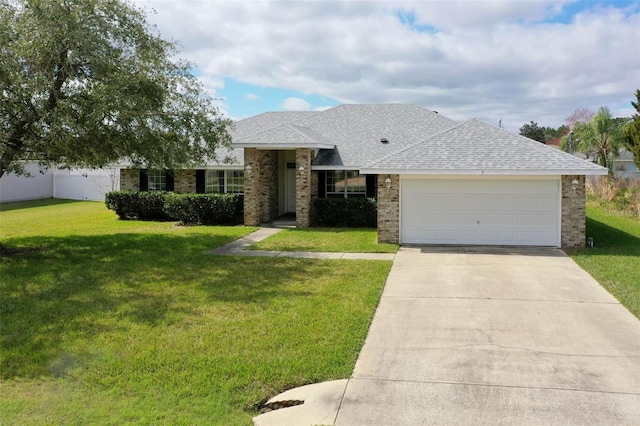 ranch-style house featuring a garage, concrete driveway, a front lawn, and roof with shingles