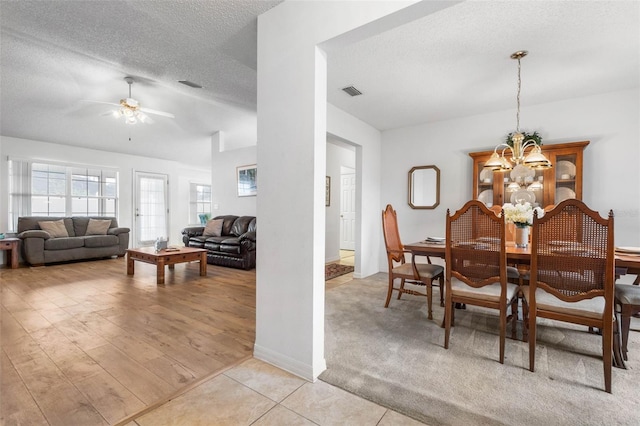 dining room featuring a textured ceiling, light tile patterned floors, ceiling fan with notable chandelier, and visible vents