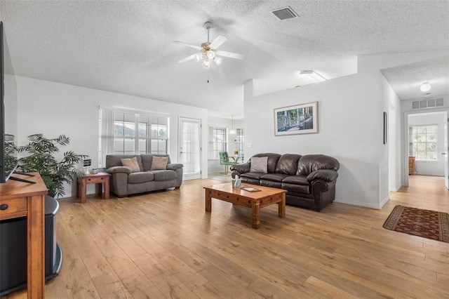 living area featuring light wood finished floors, a textured ceiling, visible vents, and a ceiling fan