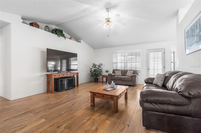 living room with vaulted ceiling, a textured ceiling, light wood finished floors, and ceiling fan