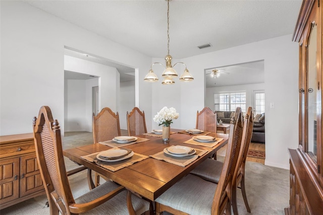 carpeted dining area featuring visible vents and a notable chandelier