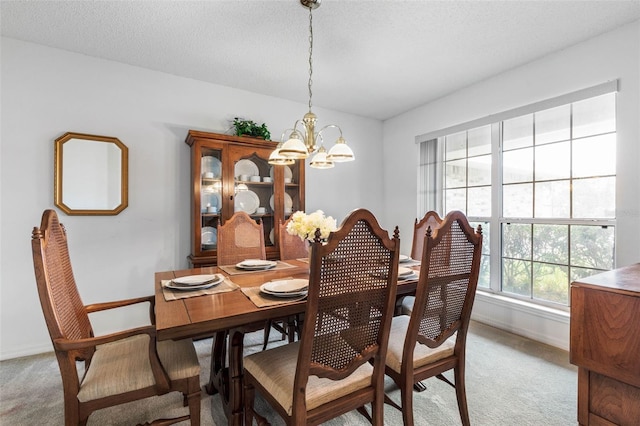 dining space featuring light carpet, a textured ceiling, baseboards, and an inviting chandelier