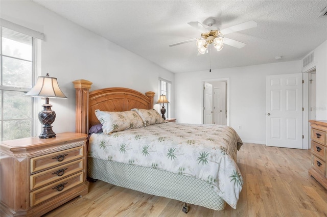 bedroom featuring visible vents, multiple windows, a textured ceiling, and light wood-style flooring