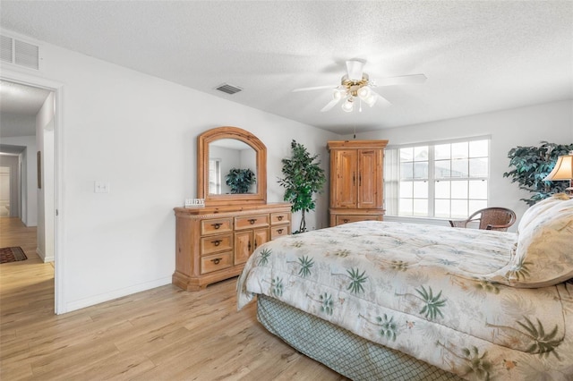 bedroom with light wood-type flooring, visible vents, and a textured ceiling