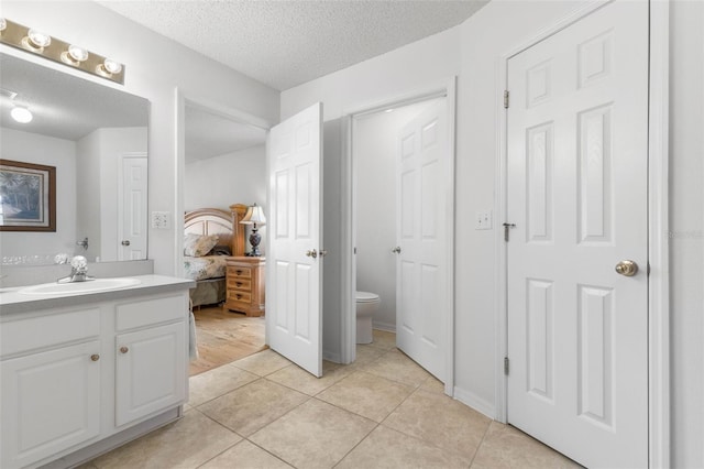 ensuite bathroom featuring tile patterned floors, a textured ceiling, toilet, and ensuite bathroom