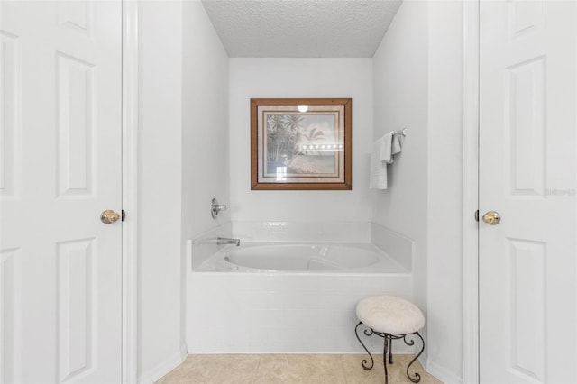 bathroom featuring a bath, a textured ceiling, and tile patterned floors