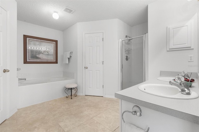 full bath with a textured ceiling, a garden tub, a sink, a shower stall, and double vanity